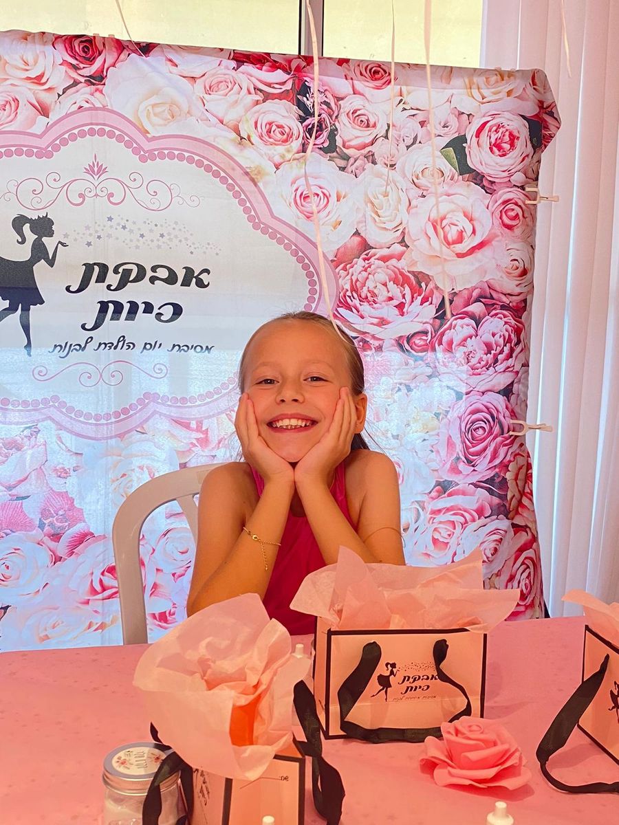 ילדה שמחה עם ידיים על הלחיים, מול שקיות מתנה ורקע ורדים עם לוגו אבקת פיות